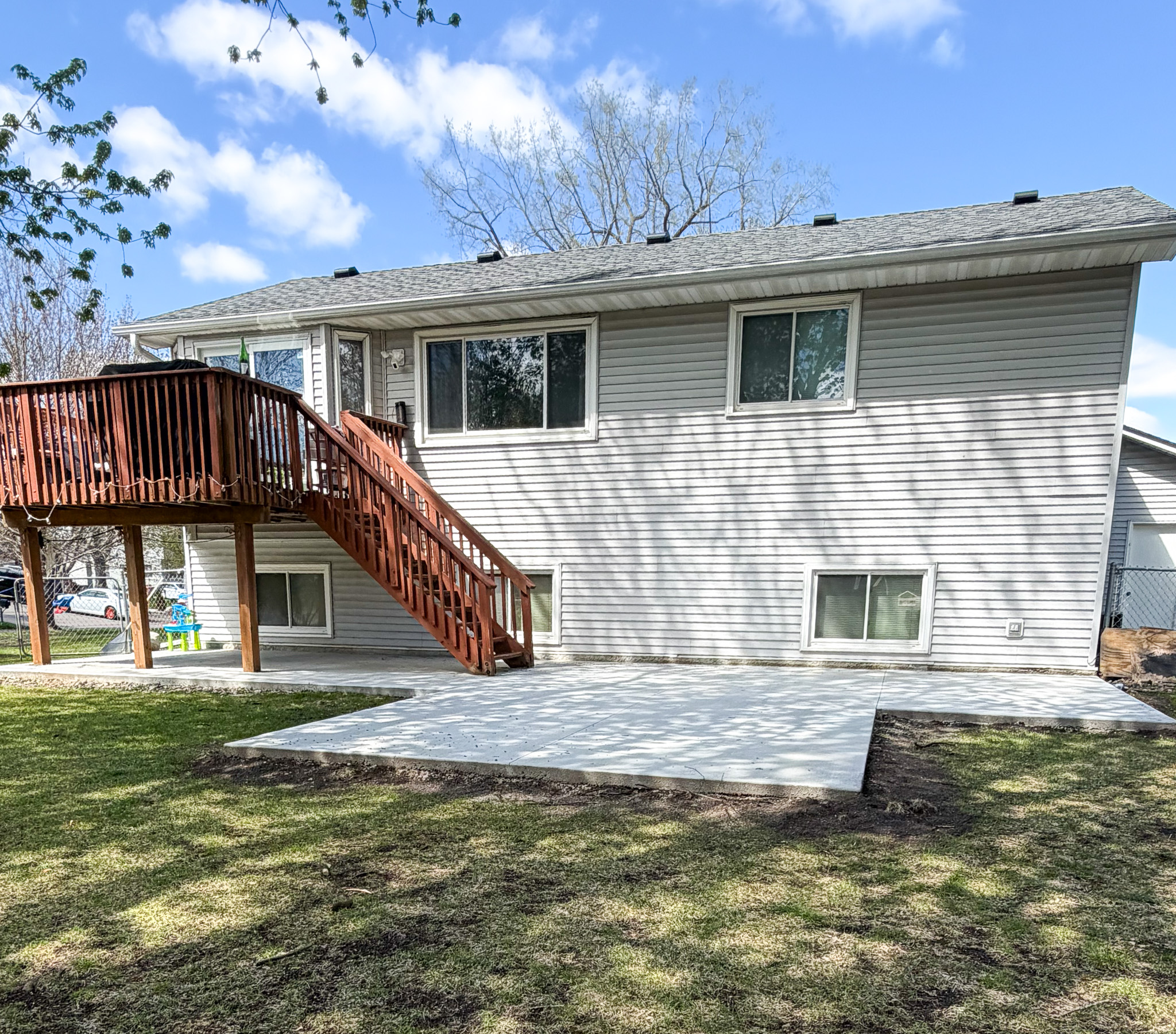 Backyard concrete patio with deck stairs by A&J Custom Concrete